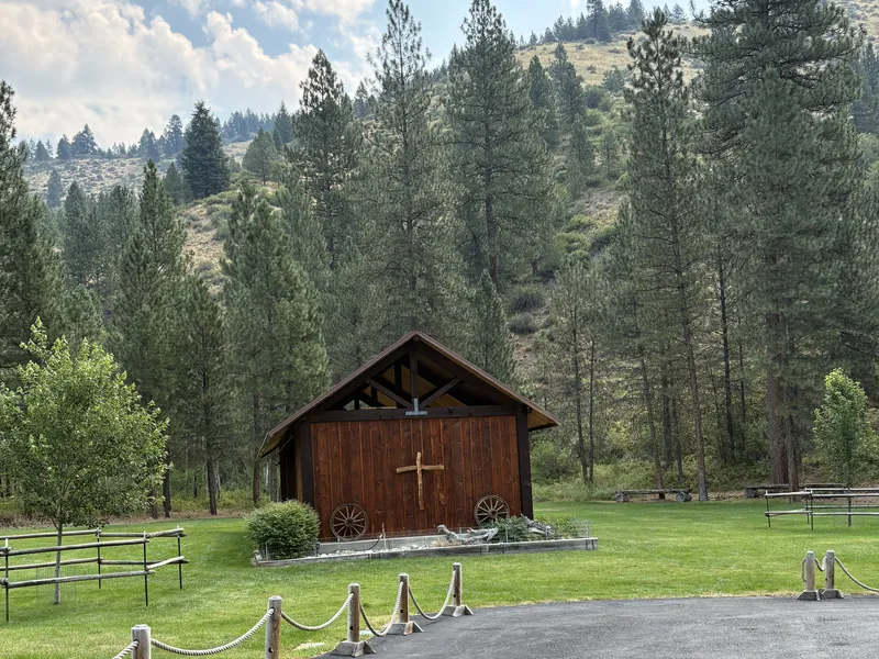 The timber chapel building with its cross, set against the wooded hillside.
