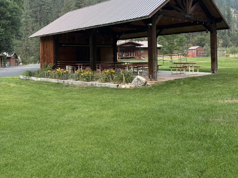 The open-sided event pavilion with flower beds along its base and lawn in front.